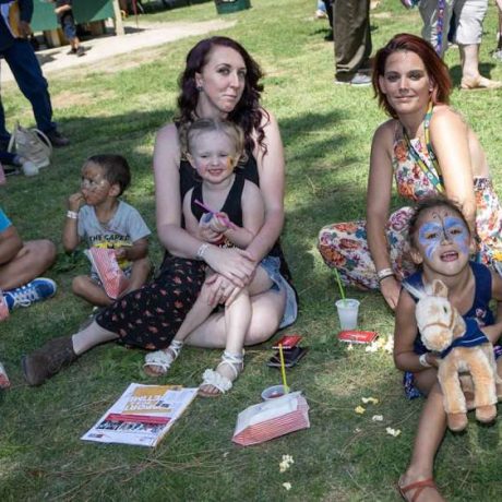 group of people smiling together for photo on a sunny day sitting on grass