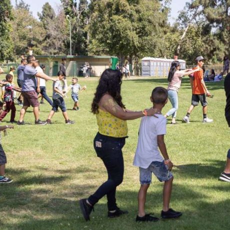 adults guiding children across grassy area