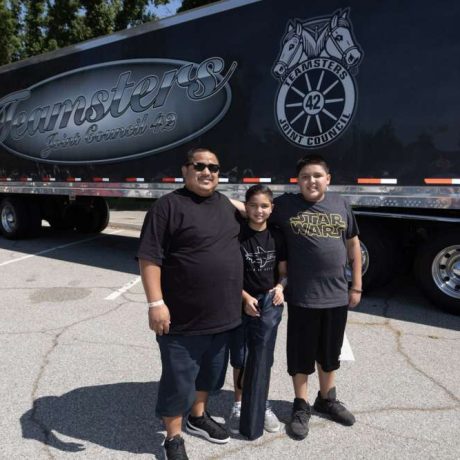 people smiling together at park for photo in front of teamsters truck