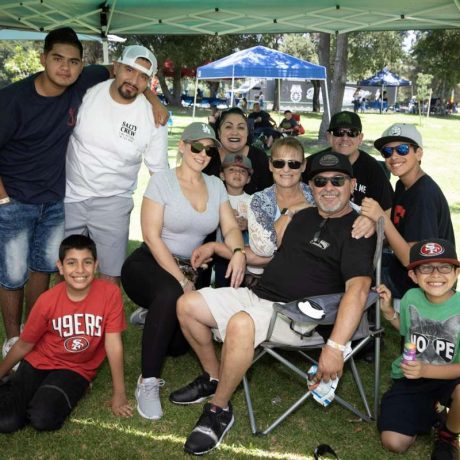 group of people smiling together for photo on a sunny day under sun shade