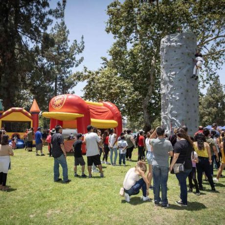 wide angle photo of picnic activities including inflatable castle and rock climbing wall