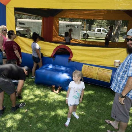 people standing around inflatable castle with children playing inside
