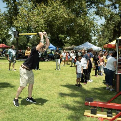 man swinging hammer for game while people watch