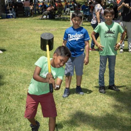 kid testing his strength on hammer game at park