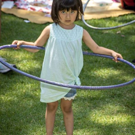 kid staring at camera playing with hula hoop