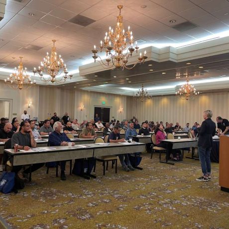 large room full of people seated at tables with chandeliers