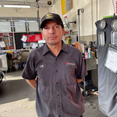 man standing with hands behind back posing for photo at work