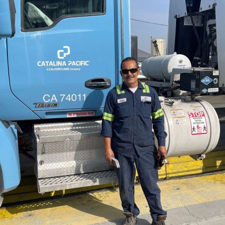 man smiling standing in work uniform in front of a truck