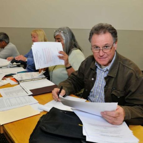 man smiling wearing glasses reviewing documents