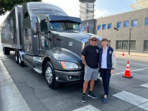 people standing in front of big rig smiling
