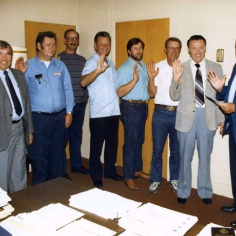 group of people smiling together with right hands held high