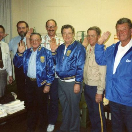 group of people smiling together with right hands held up