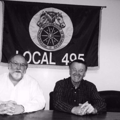 karl ullman and friend sitting together in front of local 495 sign