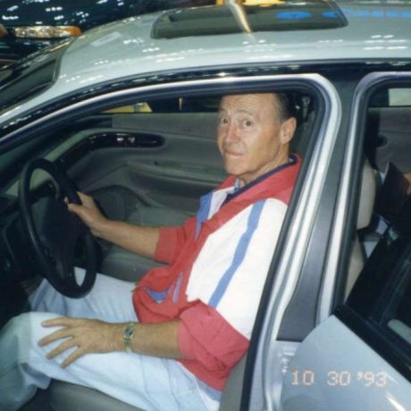 man smiling in car with open door on a show floor