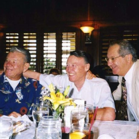 three men posing and smiling in restaurant